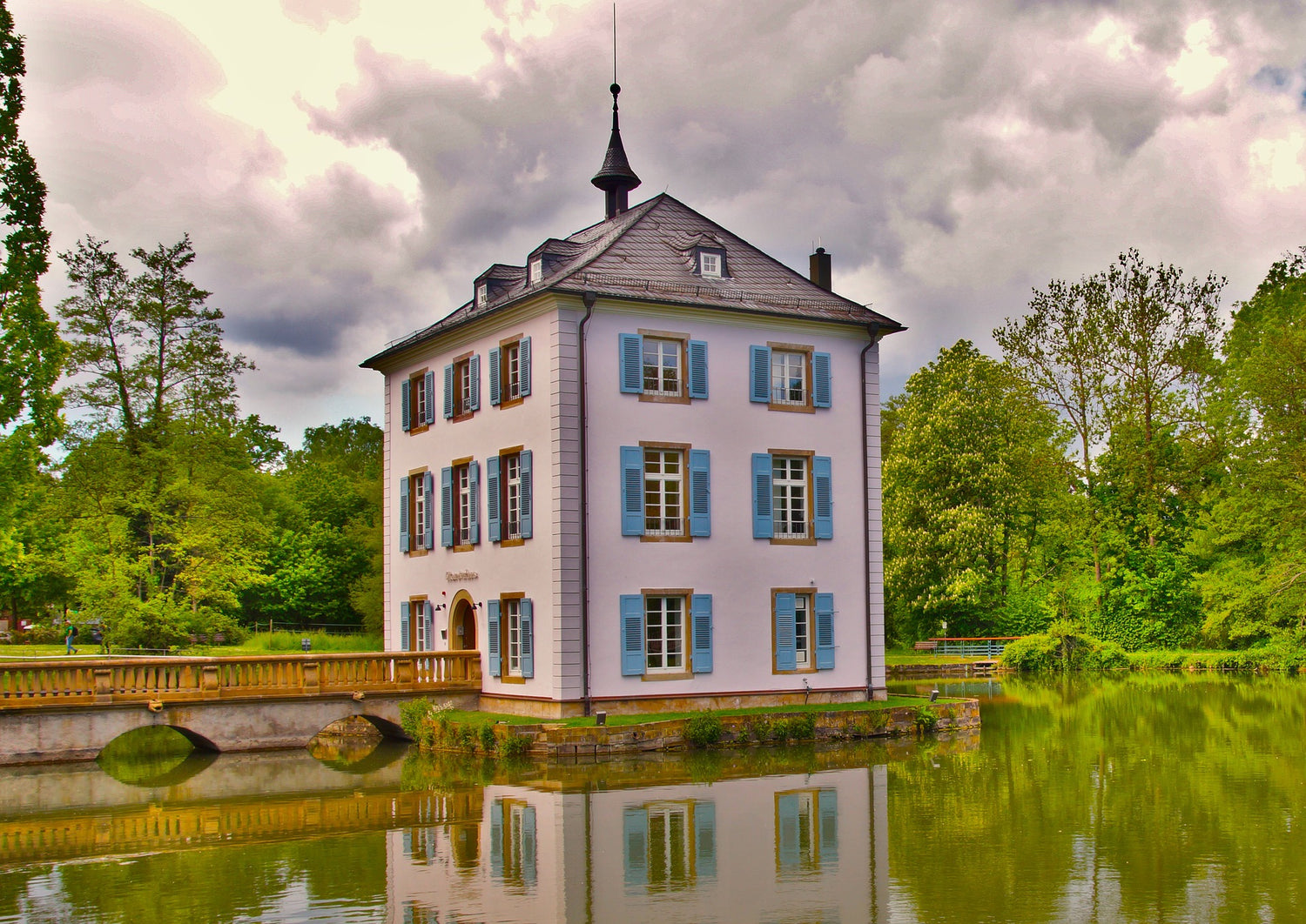 Historic lakeside building with blue shutters and bridge reflection in Heilbronn, Germany